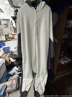 Front view of cream and grey flying squirrel onesie hanging