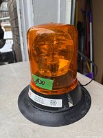 Full view of amber rotating beacon light showing dome, internal mechanism, and product label