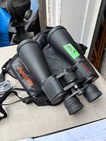 Celestron 15x70 binoculars with case, lens caps and strap visible