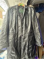 Full view of black leather coat on hanger showing front, buttons, pockets, length