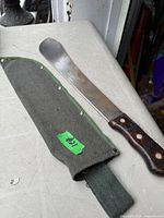Machete and sheath laid on table showing blade, handle, and sheath details