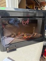 Front view of Muskoka Gold electric fireplace heater showing glass front and faux logs