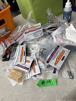 Pile of factory-sealed bags with racing hardware, springs visible, fluid bottle at top right