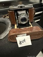 Camera in open position within case, showing lens, bellows, body and part of case