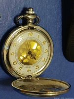 Pocket watch open showing white dial, gold numerals, skeleton center