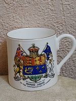 Front view of Aynsley bone china commemorative cup showing Canadian coat of arms and gold rim