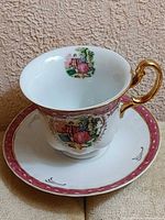 teacup on saucer showing exterior motif and gold handle