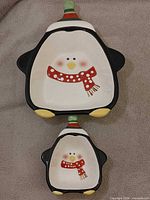 Two ceramic penguin-shaped bowls, large and small, front view