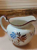 Left side view of ceramic pitcher showing floral design and handle
