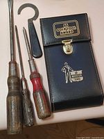 Group shot of three wood screwdrivers, rotary phone spanner, closed Chrysler award pouch