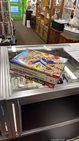 Stack of four Stan Lee related books on glass display counter