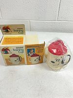 sealed Snoopy training cup next to two views of original box