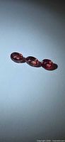 Three oval deep pink sapphires angled under light