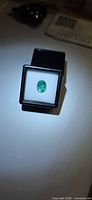 Front view of oval green emerald in display case