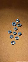 Ten round blue aquamarine gemstones on tan background