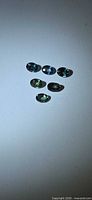 Six oval mixed-cut blue-green sapphires arranged on white background