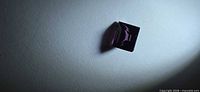 Square purple spinel on white background showing step cut facets