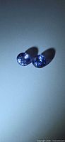 Pair of round violet-blue Tanzanite gemstones under light