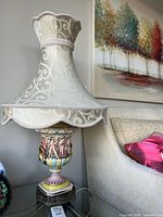 Full lamp with shade beside sofa and wall art