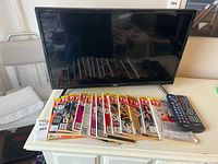 TV, magazines, and remotes on cabinet, TV powered off