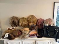 Overview of wigs, sunglasses, handbag and accessories on dresser