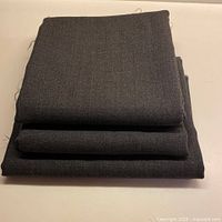 Three folded pieces of charcoal grey wool fabric