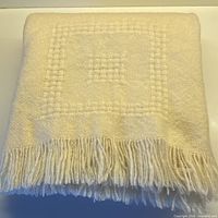 Folded cream wool throw showing color and fringe