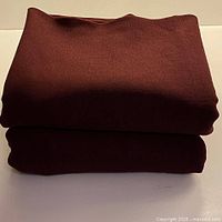 Two folded burgundy wool crepe fabric pieces stacked