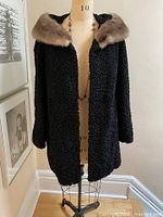 Full front view of black curly lambswool coat on dress form