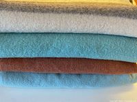 Stack of four wool blankets showing colours and textures