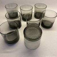 Eight smoky grey lowball tumblers, one inverted to show textured base