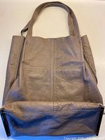 Full view of grey leather tote bag front and handles