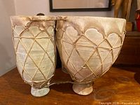 Side view showing both clay drums joined by leather strap and lacing detail