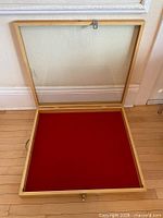 Open wood display case showing glass lid and red felt interior