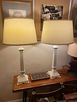 Pair of white metal column table lamps with shades displayed on table