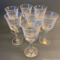 Front view of seven etched liqueur glasses with labels