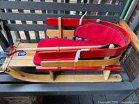 Side profile of sled showing wood construction, red rails, fleece liner