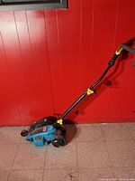 Full view of blue electric lawn edger with handle and wheels