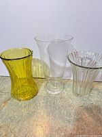 Front view of all three vases: yellow ribbed, clear trumpet, clear ribbed scalloped