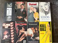 All eight VHS tapes laid out, showing titles and one loose cassette