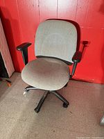 Full view of grey fabric office chair against red wall
