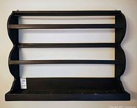 Front view of black wooden plate rack showing four tiers