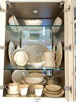 Cabinet view showing multiple plates, bowls, cups, serving pieces