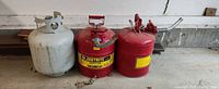Front view of propane cylinder and two red Justrite safety cans