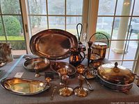 Full lot overview on table showing platters, covered dish, candlesticks, spoons, bucket