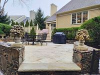 Pair of cast stone fruit basket urns on patio walls