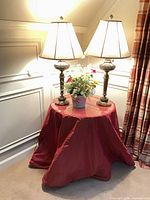 Round table with red skirt, glass top, two lamps, faux flowers