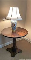 Round wood pedestal side table with lamp on top, front view