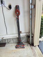 Full view of Shark Rocket stick vacuum standing upright against wall