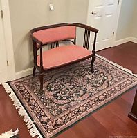 Settee positioned on floral rug showing full view of both items